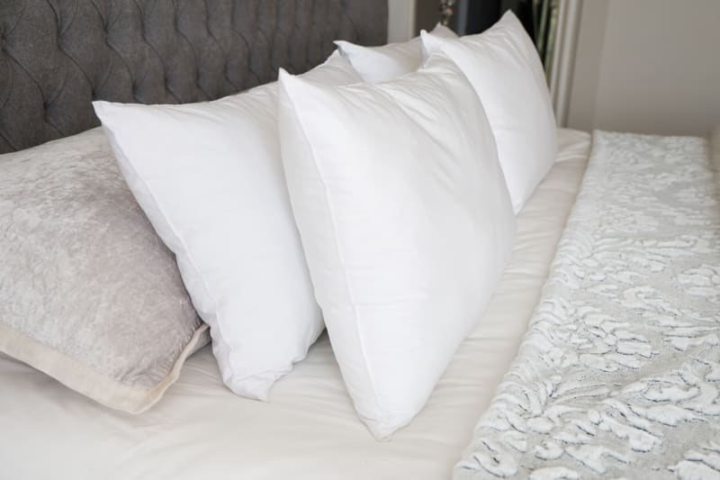 White pillows arranged on a bed with a lace runner