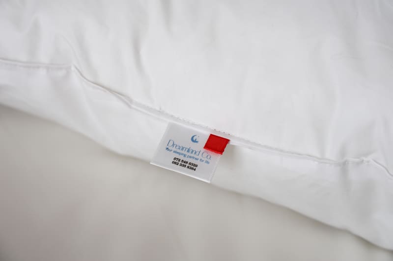 Sewn-in Dreamland Co. care label with a red colour tab on the pillow seam