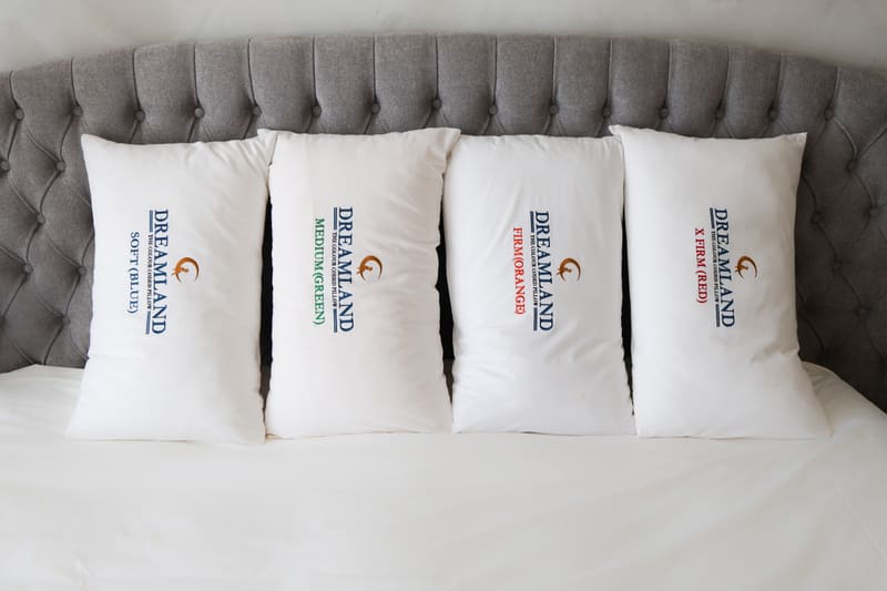 Four Dreamland pillows standing upright against a tufted headboard