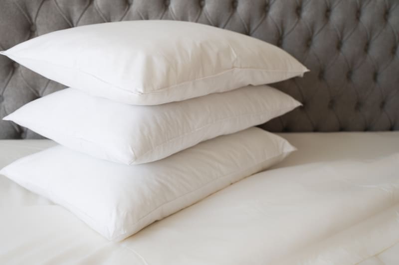 Three white pillows stacked on a bed