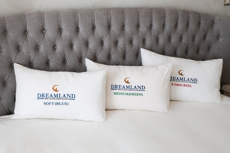 Three Dreamland pillows in front of a grey headboard